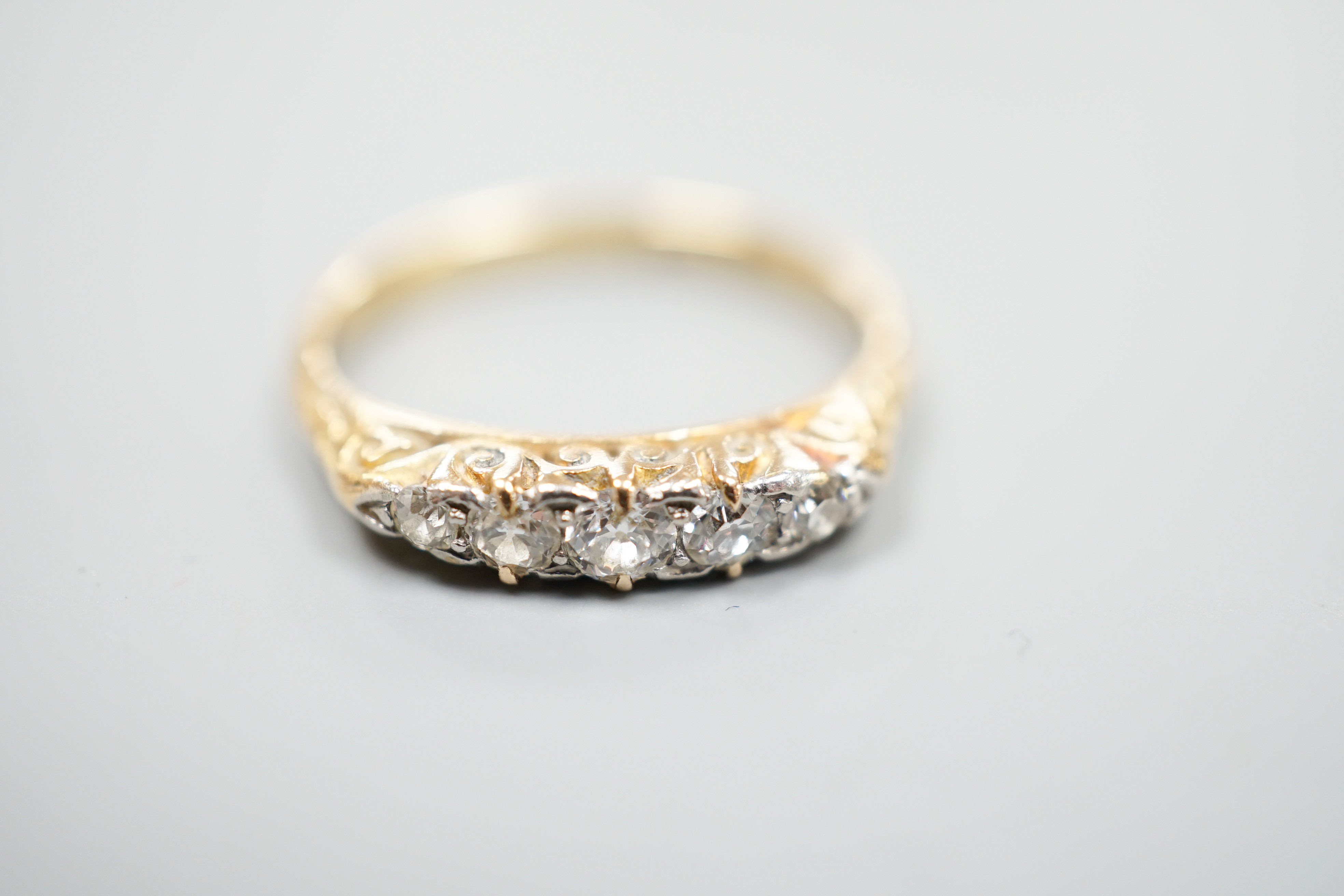 An 18ct and graduated five stone diamond set half hoop ring, size O, gross weight 3 grams.